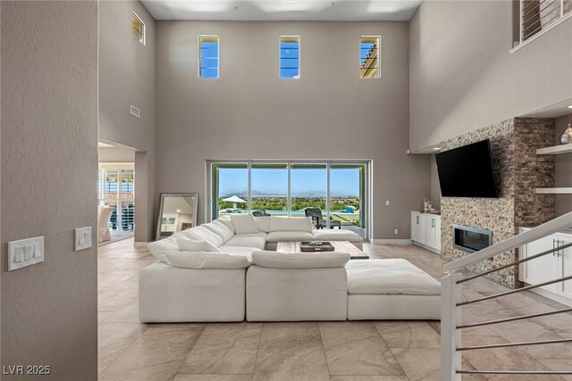 living room featuring a glass covered fireplace, plenty of natural light, and a towering ceiling