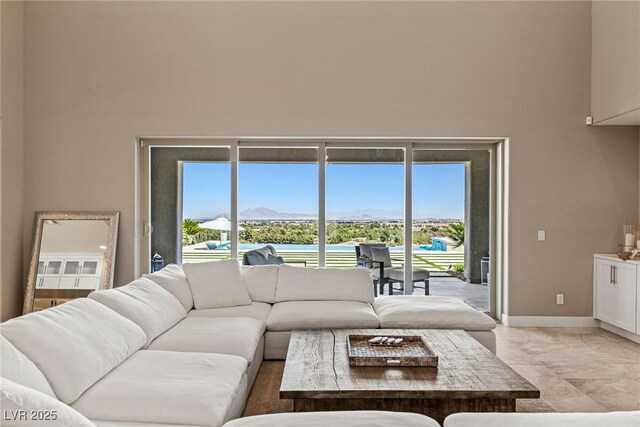living room with baseboards, a high ceiling, a mountain view, and marble finish floor