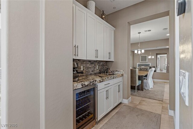 bar featuring visible vents, beverage cooler, a sink, backsplash, and a notable chandelier