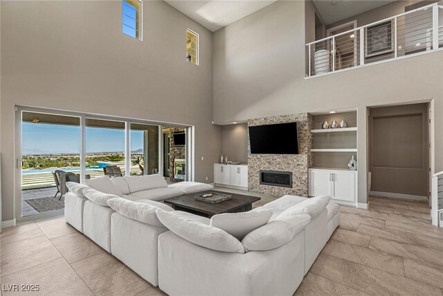 living area featuring baseboards, a high ceiling, a wealth of natural light, and built in shelves
