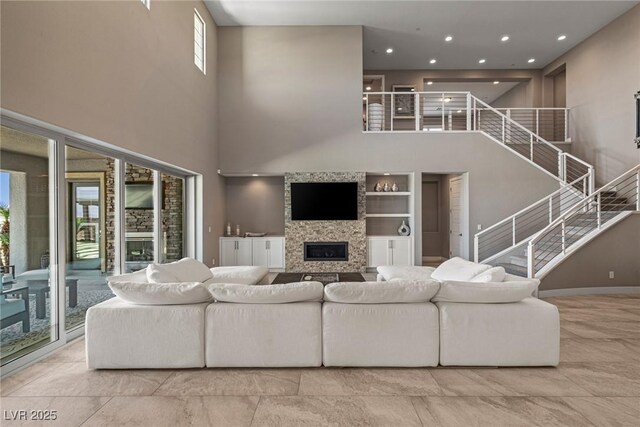living room with recessed lighting, a glass covered fireplace, and a high ceiling