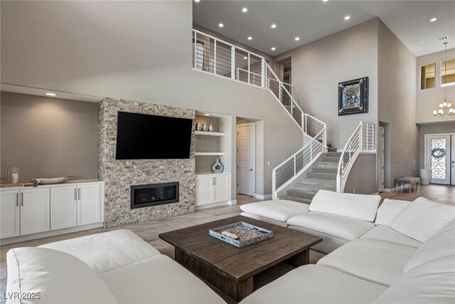 living area featuring a stone fireplace, built in features, baseboards, a high ceiling, and recessed lighting
