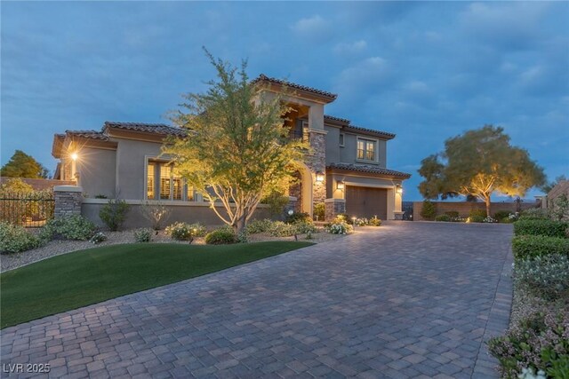 view of front of home featuring a garage, stucco siding, a balcony, a tiled roof, and driveway