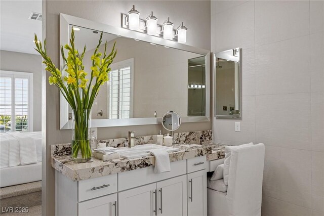 ensuite bathroom with connected bathroom, visible vents, and vanity