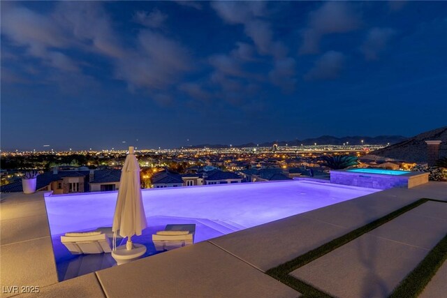 pool at twilight featuring an in ground hot tub and an infinity pool