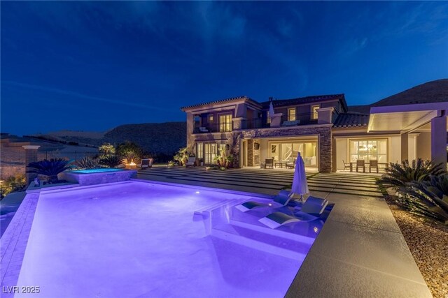 pool at twilight featuring a patio, an in ground hot tub, and an outdoor pool