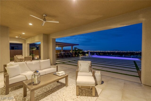 patio at night with outdoor dining area, a ceiling fan, and an outdoor hangout area