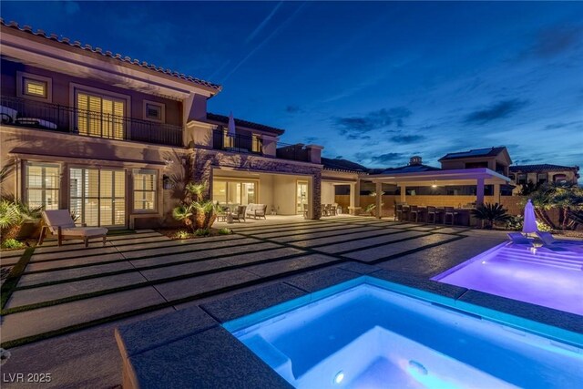 pool at twilight with a patio, an outdoor bar, french doors, a fenced in pool, and an in ground hot tub