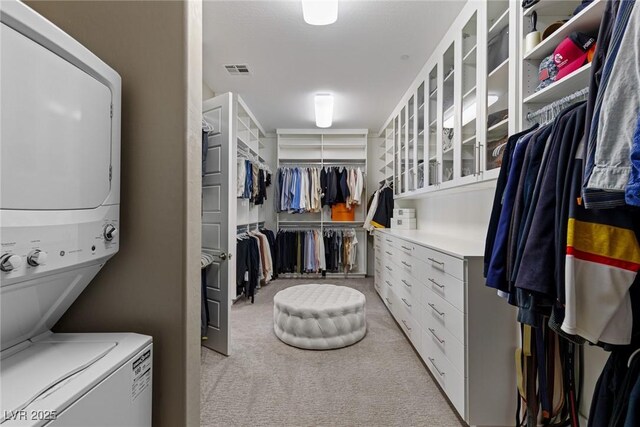 interior space featuring visible vents, laundry area, stacked washer / dryer, and light carpet