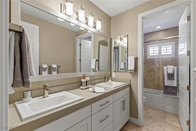 bathroom featuring shower / bath combination with glass door, a sink, double vanity, and toilet