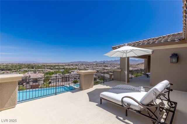 view of patio / terrace with a fenced in pool, a mountain view, and a balcony