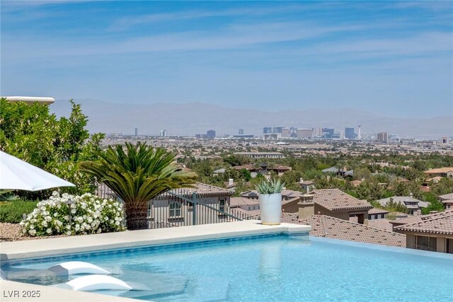outdoor pool with fence, a view of city, and a mountain view