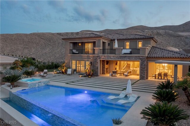 rear view of property with a patio area, stucco siding, and a balcony