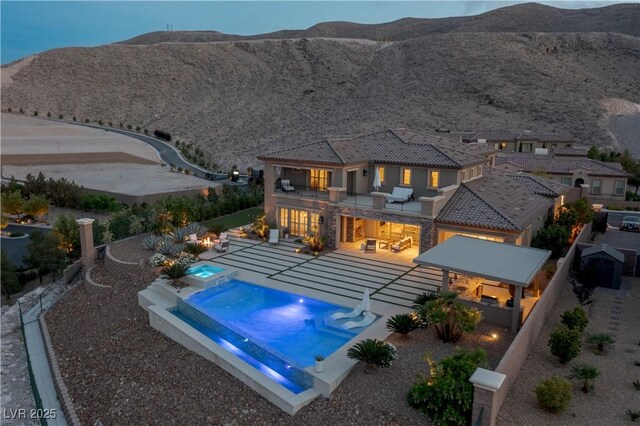 view of pool featuring a patio, a fenced backyard, a mountain view, and a pool with connected hot tub