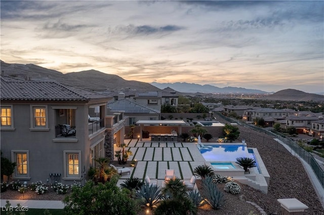 2 Olympia Outlook Dr, Las Vegas, NV 89141 - pool at dusk featuring a mountain view, a fenced backyard, a pool with connected hot tub, and a patio
