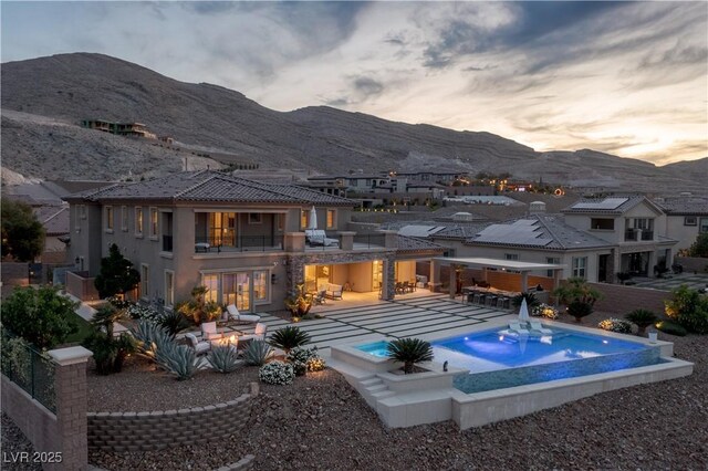 view of pool featuring a residential view, an infinity pool, a jacuzzi, a mountain view, and a patio area