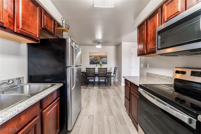 5020 Indian River Dr Unit 424, Las Vegas, NV 89103 - kitchen with light wood-type flooring, reddish brown cabinets, light countertops, a sink, and appliances with stainless steel finishes