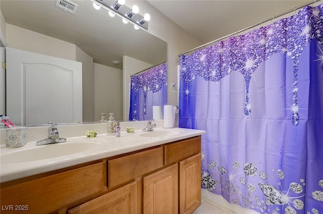 bathroom featuring a sink, tile patterned floors, double vanity, and visible vents