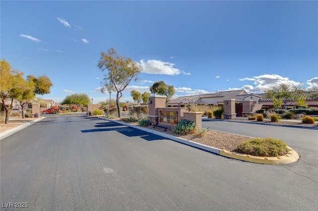 view of street featuring curbs, a gated entry, and a residential view