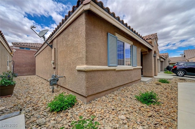 view of home's exterior with a tile roof and stucco siding