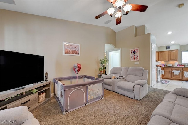living area featuring visible vents, lofted ceiling, light carpet, ceiling fan, and arched walkways