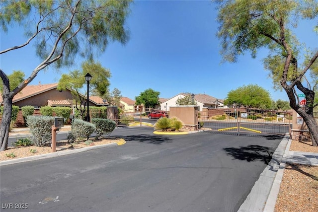 view of street with a residential view, a gate, a gated entry, and curbs