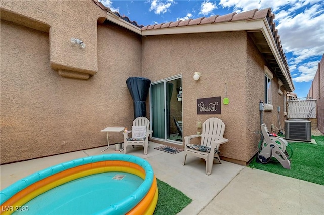 back of property featuring stucco siding, a patio area, central AC, and fence