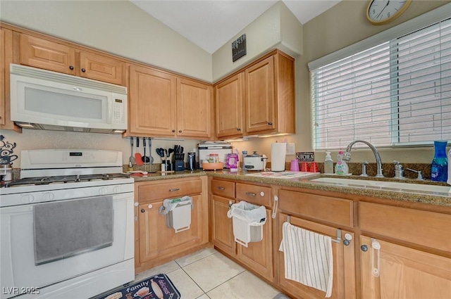 kitchen featuring a sink, light stone counters, lofted ceiling, white appliances, and light tile patterned flooring