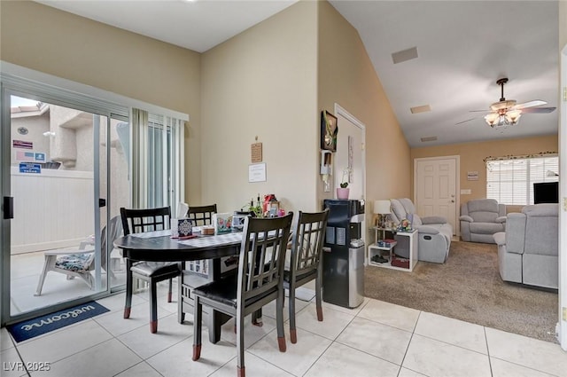 dining room featuring light tile patterned floors, a ceiling fan, vaulted ceiling, and light colored carpet