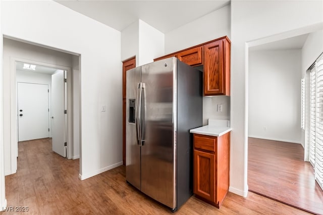 10029 Netherton Dr, Las Vegas, NV 89134 - kitchen with baseboards, stainless steel refrigerator with ice dispenser, light countertops, brown cabinets, and light wood-style flooring