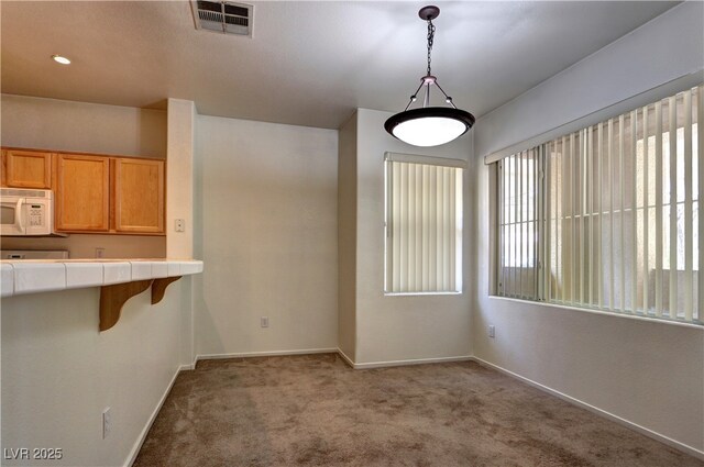 unfurnished dining area with carpet floors, baseboards, and visible vents