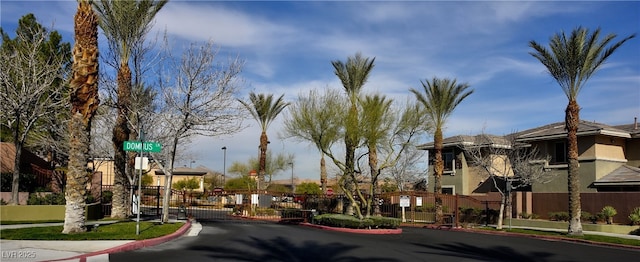 view of road with traffic signs, a gate, sidewalks, and curbs