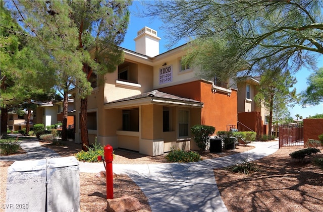 exterior space with fence, a chimney, a gate, and stucco siding