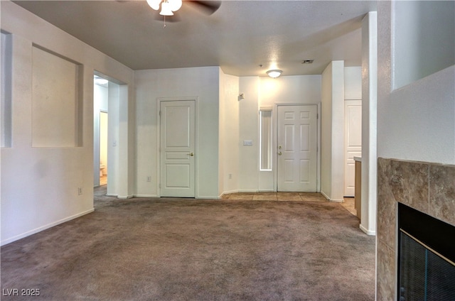 unfurnished living room featuring ceiling fan, visible vents, a fireplace, baseboards, and carpet flooring