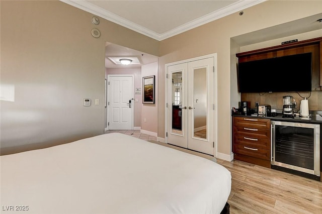 bedroom featuring french doors, baseboards, light wood finished floors, beverage cooler, and ornamental molding