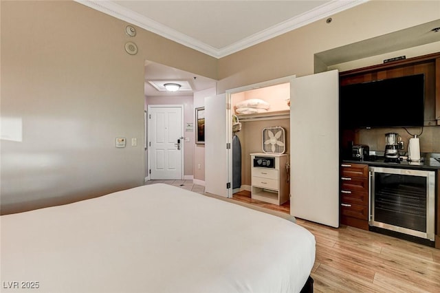 bedroom with crown molding, beverage cooler, a spacious closet, and light wood-style flooring