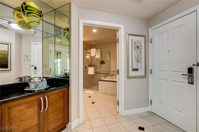 full bathroom featuring vanity, tile patterned floors, baseboards, a stall shower, and tiled tub