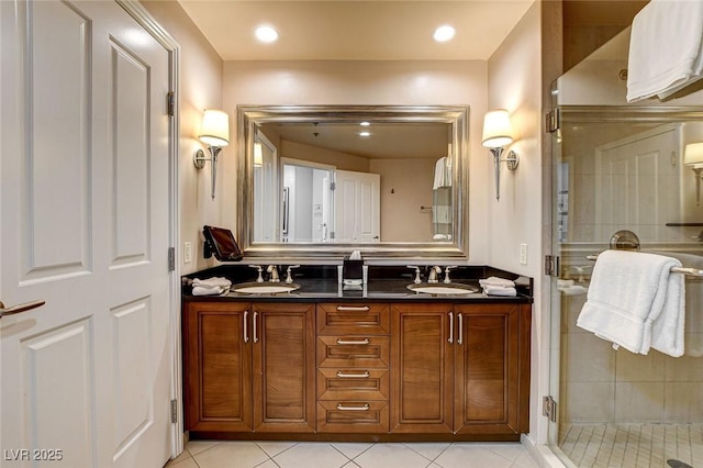 full bath with double vanity, tile patterned floors, a shower stall, and a sink