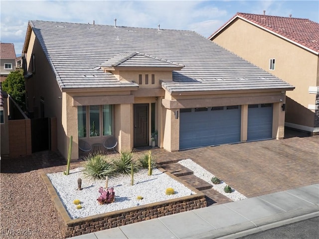 view of front of house with stucco siding, an attached garage, a tile roof, and decorative driveway