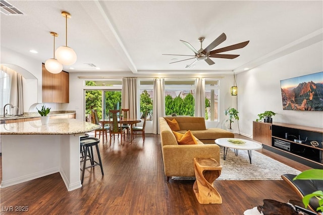 living area featuring dark wood-style flooring, a ceiling fan, visible vents, and a wealth of natural light