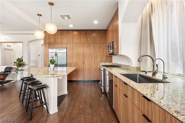 kitchen with a kitchen bar, visible vents, modern cabinets, a sink, and stainless steel appliances