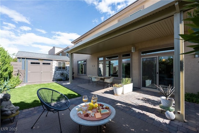 view of patio / terrace featuring a storage unit, outdoor dining area, and an outbuilding