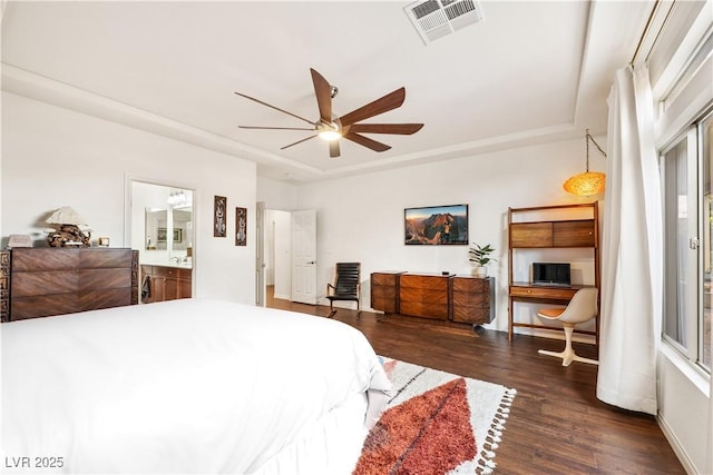 bedroom featuring ceiling fan, a raised ceiling, baseboards, wood finished floors, and visible vents