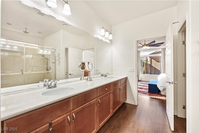 ensuite bathroom with connected bathroom, a sink, double vanity, a shower stall, and wood finished floors