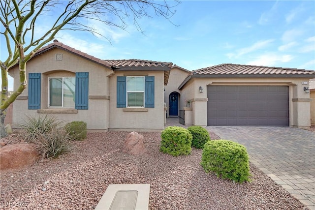 view of front of home featuring a garage, a tiled roof, decorative driveway, and stucco siding