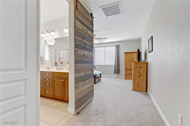 corridor with baseboards, visible vents, and light carpet