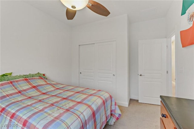 bedroom with ceiling fan, light colored carpet, and a closet
