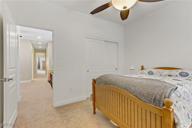 bedroom with baseboards, a ceiling fan, a closet, and light colored carpet