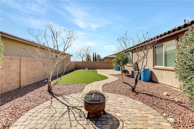 view of yard with a fenced backyard, a patio area, and an outdoor fire pit