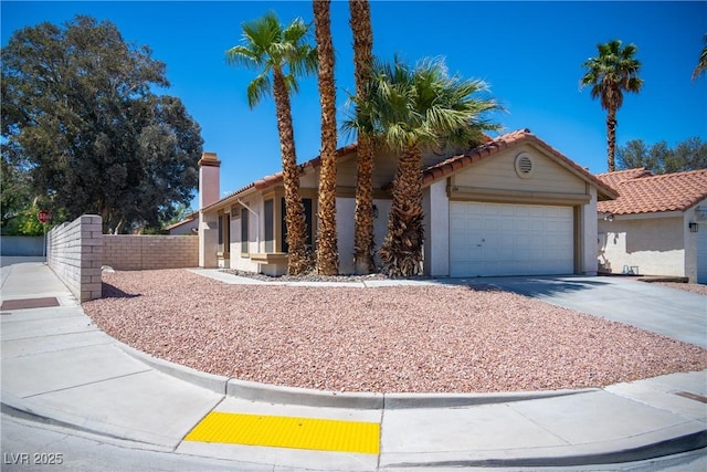 view of front of property with a tiled roof, driveway, fence, an attached garage, and stucco siding